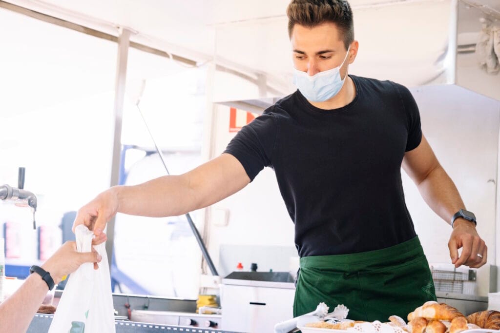 Commerçant ambulant remettant un sac à un client avec un terminal de paiement mobile