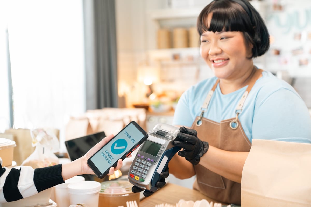  Une commerçante fait payer sans contact un client avec un terminal de paiement (TPE) en 2026