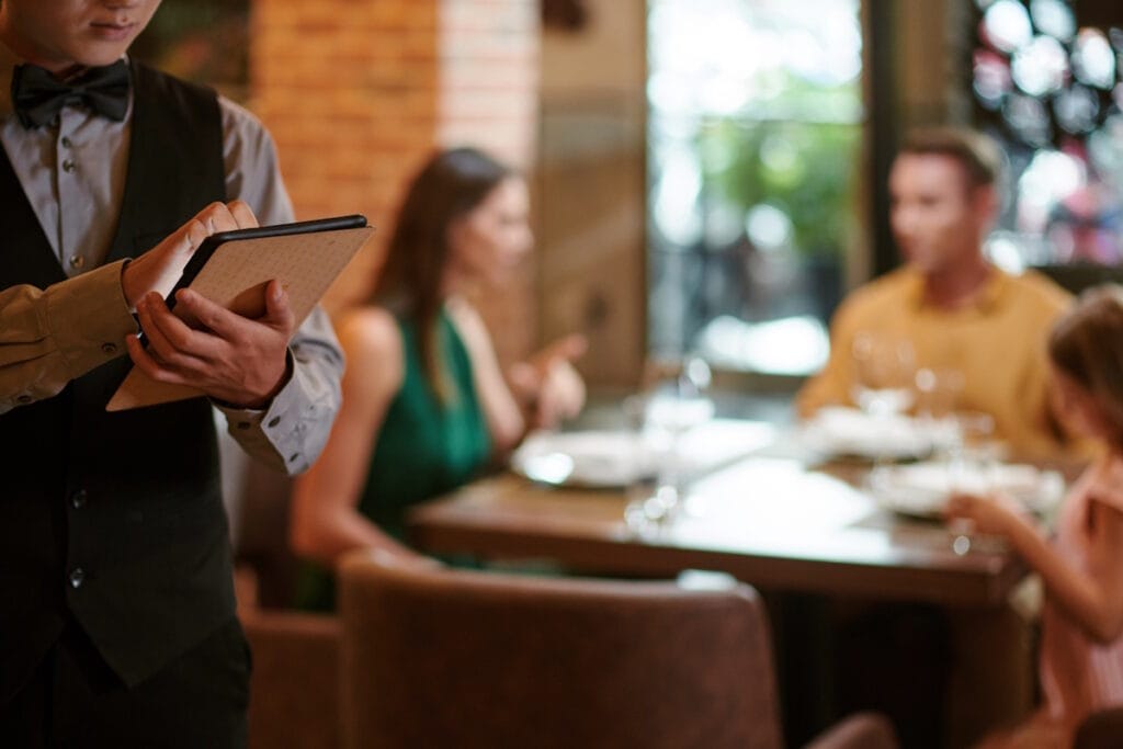 Dans un restaurant, un serveur utilise une tablette connectée