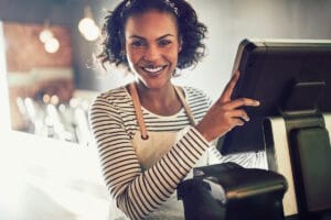 Jeune femme souriante devant sa caisse tactile