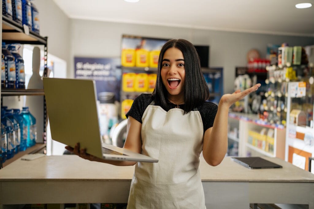 Jeune commerçante heureuse tenant un pc portable