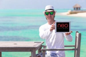 Jeune homme seul sur une plage brandit une tablette Neo Systems