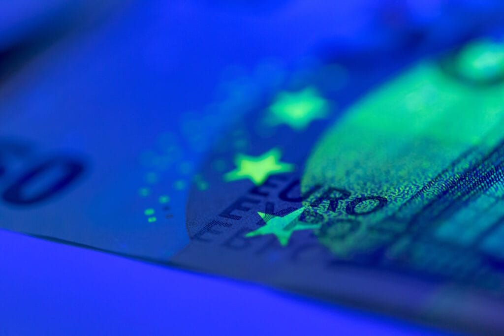 Billet de 50 euros sous éclairage UV révélant ses dispositifs d'authenticité