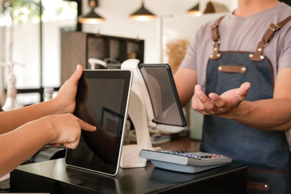 Vue sur un commerçant et un client autour de deux tablette tactiles