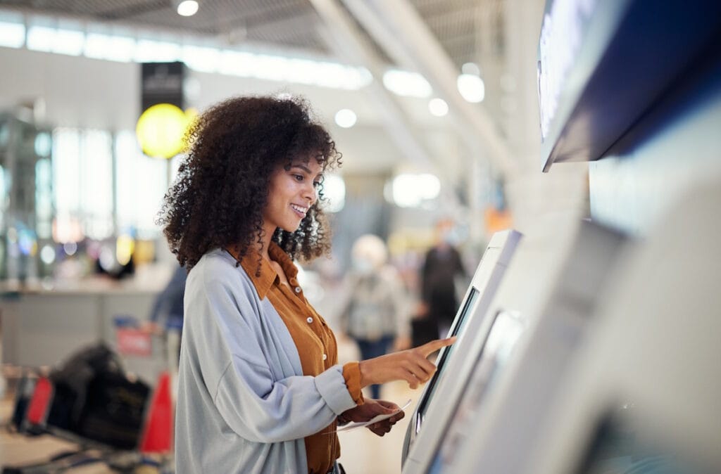 Une jeune femme souriante paye ses achats en utilisant une caisse tactile