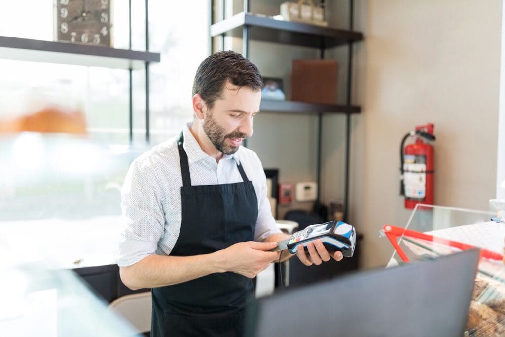 Un commerçant contrôle la sécurité de son TPE avant d'encaisser le paiement CB