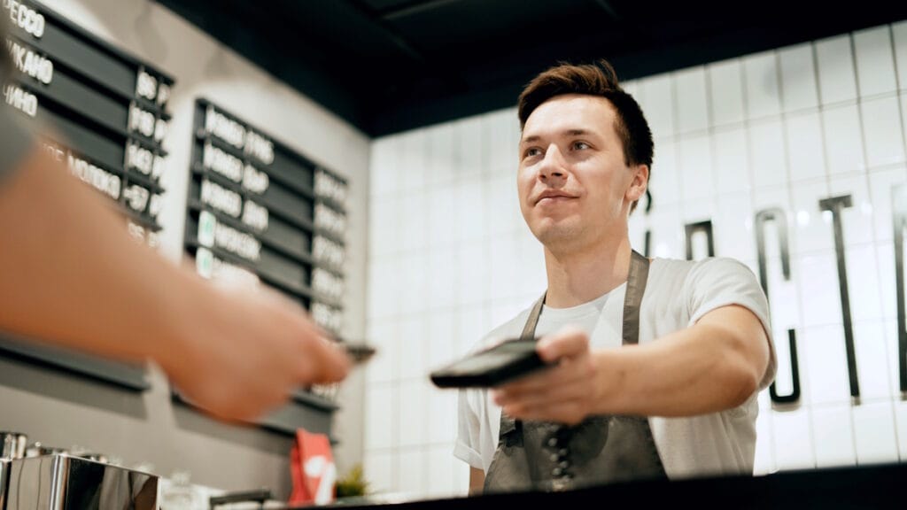 Un serveur présente un TPE sécurisé au client pour encaisser par carte