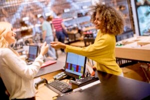 Une jeune femme règle ses achats dans un magasin disposant de plusieurs caisses enregistreuses tactiles