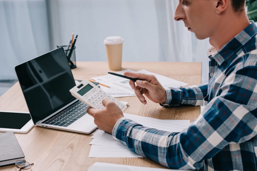 Jeune commerçant en train de calculer les frais de son contrat monétique