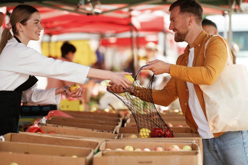 Client souriant réglant ses achats sur un marché