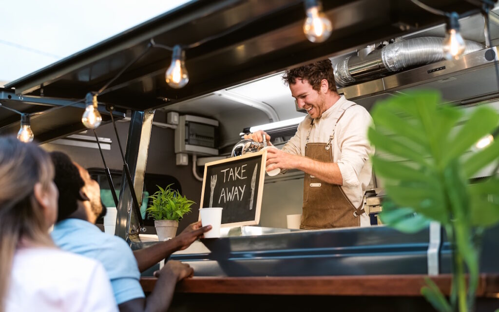 Jeune homme souriant sert des biĂšres Ă la pression en food truck