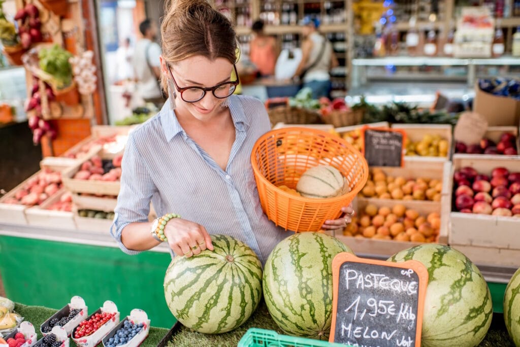 Jeune femme choisissant des fruits pour son client sur un marché